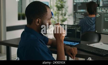 African american system engineer thinking about html script development to code it language in agency office. Software developer brainstorming ideas to write artificial intelligence algorithm. Stock Photo