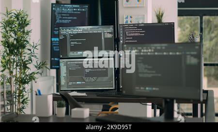 Computer screens on desk in empty data room displaying program code and algorithms, developing new user interface. Agency network servers with cloud computing script in software it office. Stock Photo