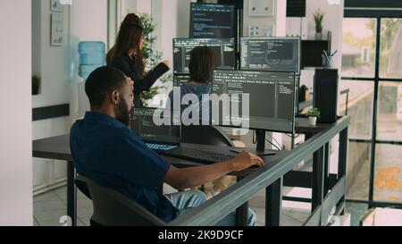 African american coder writing programming language on computer, using database code to develop server interface. System engineer analyzing html script and cloud computing in it development agency. Stock Photo