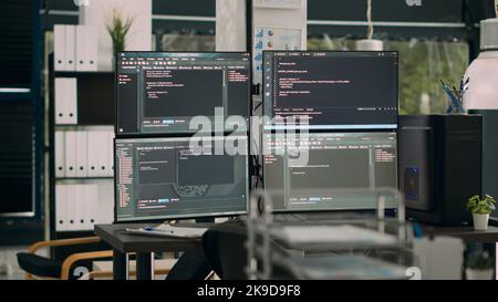 Monitors displaying parsing code in empty it agency office desk with computers compiling data algorithms. Artificial intelligence servers cloud computing with html script on temrinal window. Stock Photo