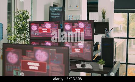 Desk with multiple monitors displaying error message on screen, computer server being hacked. Empty software developing agency office with system error security and hacking alert. Stock Photo