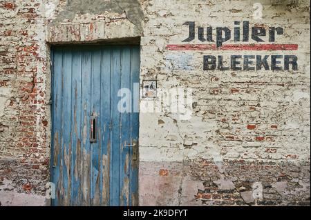 Old blue door in a white washed brick wall with Jupiler Bleeker stencilled alongside