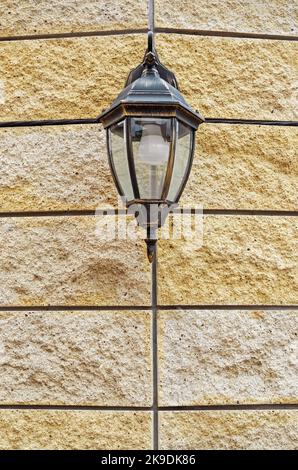 Wall mounted street lamp mounted on stone fence on made volcanic tuff Stock Photo