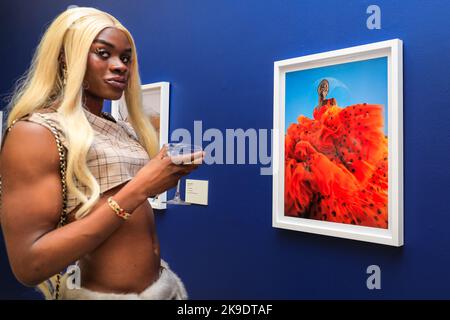 London, UK. 27th Oct, 2022. A guest poses with Nadine Ijewere's Joy As An Act Of Resistance, 2018. Invited guests and artists mingle and pose with the images. Private view of the new exhibition 'The New Black Vanguard: Photography Between Art and Fashion' at Saatchi Gallery in London, supported by Burberry. The exhibition features 15 international Black photographers and is a celebration of Black creativity both in-front of and behind the camera, running until Jan 22, 2023. Credit: Imageplotter/Alamy Live News Stock Photo