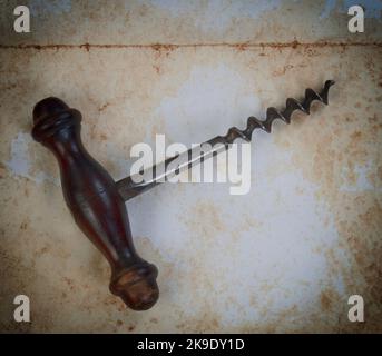 Vintage wine corkscrew on faded paper texture background in close up view Stock Photo