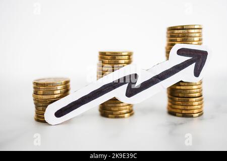 growing stacks of coins with arrow going up, concept of prices becoming more expensive or savings and compound interests increasing Stock Photo