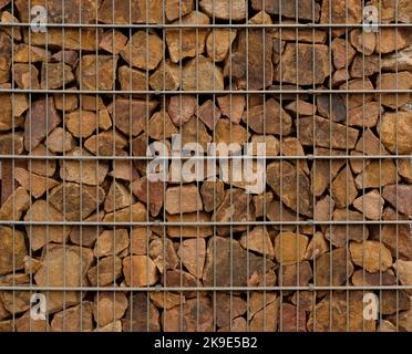 Gabion retaining wall - close-up brown stones in gabion metallic baskets kept by retaining wall.  Stock Photo