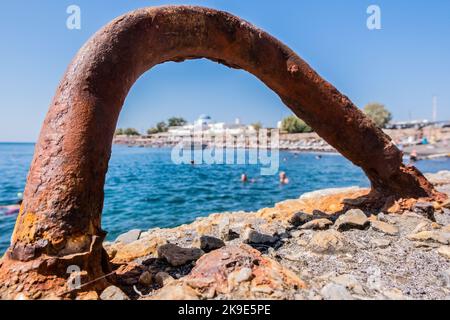 Rusty metal hook on the pier with the beach in the background Stock Photo