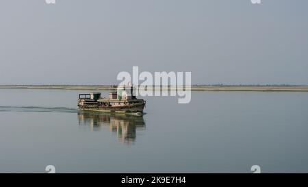 Scenic landscape view of small wooden ferry boat crossing the mighty Brahmaputra river in Assam, India Stock Photo