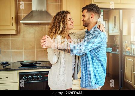 Were always doing something out of the ordinary. a young couple dancing in the kitchen at home. Stock Photo