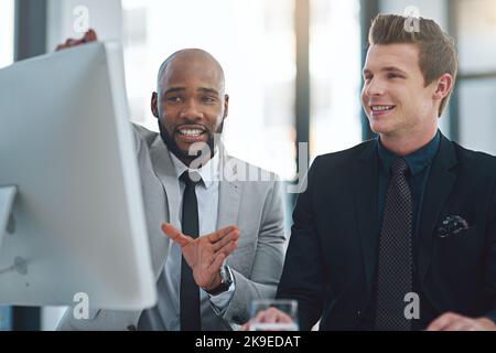 With this idea well go big. two young businessmen having a discussion while working on a computer in a modern office. Stock Photo