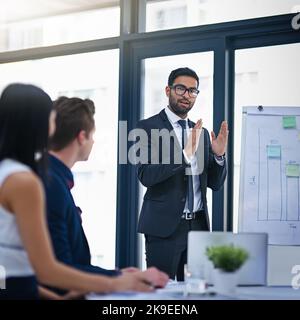 If we can directly combat these two factors well succeed. a young businessman giving a demonstration on a white board to his colleagues in a modern Stock Photo