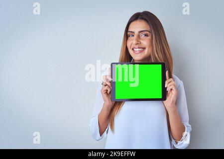 No catfish detected. Portrait of an attractive young woman holding a digital tablet against a blue background. Stock Photo