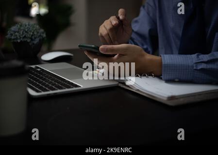 business man working on laptop computer and using mobile phone on desk digital technology concept. Stock Photo