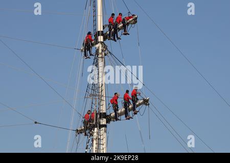 Crew of the Royal Oman Navy’s three mast square rigged clipper SHABAB OMAN II man the rigging as the ship enters harbour Stock Photo