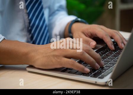 male hands typing on keyboard laptop at the office.search information form internet working on computer concept for technology. Stock Photo