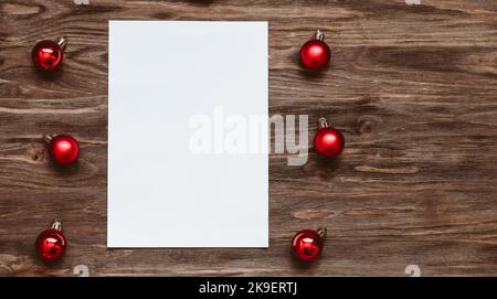 A blank sheet of paper and and red Christmas balls on a wooden background. Top view, flat lay Stock Photo