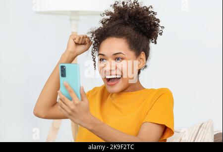 Excited young woman using mobile phone shopping online Stock Photo