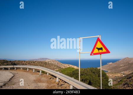 A yellow and red road sign of cows in Ios Greece Stock Photo