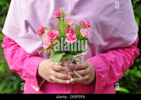 Holding plastic flower arrangements of various colors in pots selective focus Stock Photo
