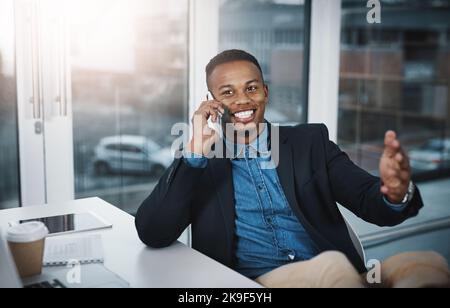 He knows what to say to seal deals. a handsome young businessman talking on a cellphone while working in an office. Stock Photo
