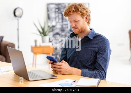 Concentrated man entrepreneur using smartphone, working, writes message using mobile phone discussing something Stock Photo