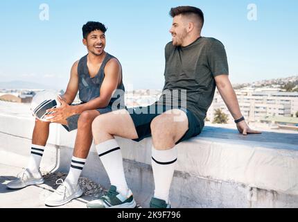Friends, sports and talking after soccer game on rooftop for urban sports, exercise and training outdoor in summer. Athlete men have conversation Stock Photo