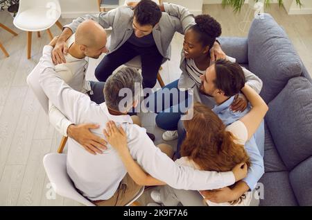 Team of happy diverse multiracial friends hugging, supporting each other and smiling Stock Photo