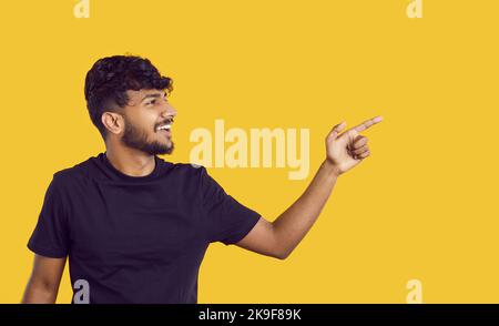 Cheerful Indian guy presenting you good offer or promotional deal on banner background. Stock Photo
