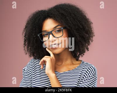 Remember, youre beautiful. a beautiful young woman posing with reading glasses against a pink background. Stock Photo