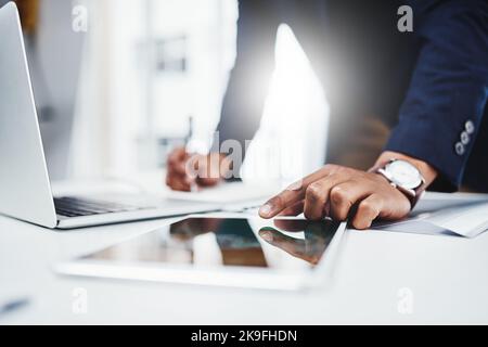 Learn how to multitask, things get really busy here. Closeup shot of an unrecognizable young businessman taking notes down from his digital tablet at Stock Photo