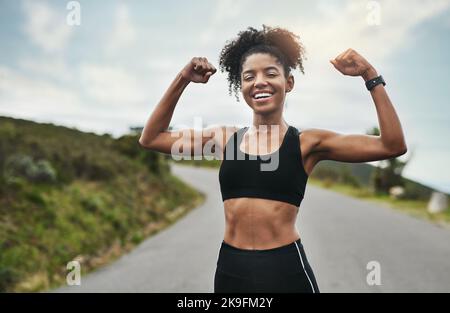 How you like me now. Cropped portrait of an attractive young sportswoman flexing her biceps outside. Stock Photo