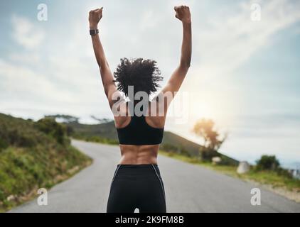 She beat her previous best. Rearview shot of an unrecognizable young sportswoman cheering in celebration outside. Stock Photo