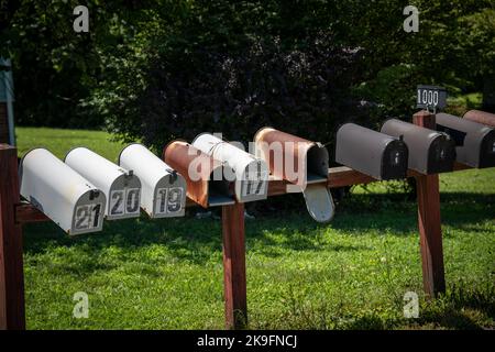 Nine, old, white, black and rusty American mailboxes with house numbers on them Stock Photo