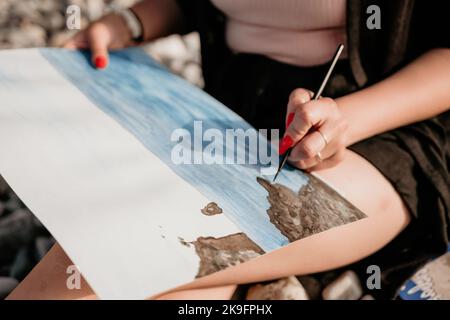 Unrecognizable woman's hands holding her own sea beach scenery watercolor painting. Amateur painter. Creative female artist drawing the picture at the Stock Photo