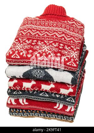 Stack of folded knitted Christmas turtleneck sweaters or pullovers with nordic ornament isolated on white background Stock Photo