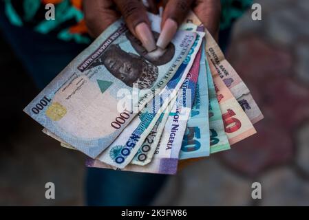 A person holding money: The Bank of Nigeria plans to redesign the Naira note. Showcase a variety of Nigerian banknotes. Stock Photo