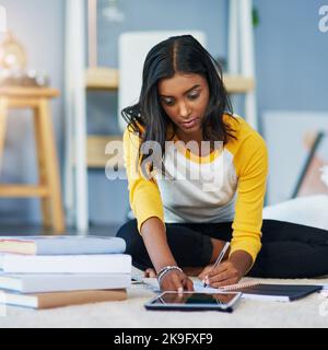 Making notes while studying helps. a young female student studying at home. Stock Photo