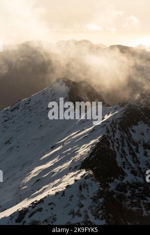 A beautiful aerial view flying over the Fiordland National Park in the late afternoon with golden light reflecting off the Tasman Sea and snowy peaks. Stock Photo