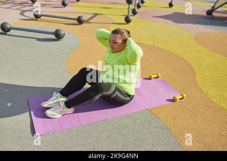 Outdoor training. Weight lost concept. Young woman doing fitness exercises at street public sports ground. Sunny autumn day. Sport, health, plans Stock Photo