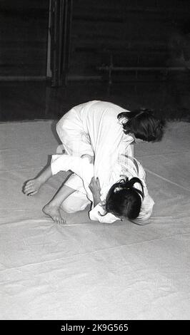 1970s, historical, inside, on a mat, two girls competing in the sport of judo, a physical activity that involves two people wrestling and trying to throw each other to the ground. Judo is a Japanese word meaning 'art of gentleness' and derives from the ancient Japanese martial art of jujitsu. Stock Photo