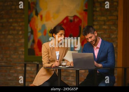 Two happy business managers are sitting and working in a cafe bar, on a beautiful sunny day Stock Photo