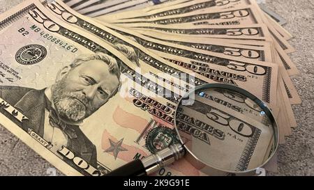 A closeup of a pile of United States dollar banknotes under a magnifying glass Stock Photo