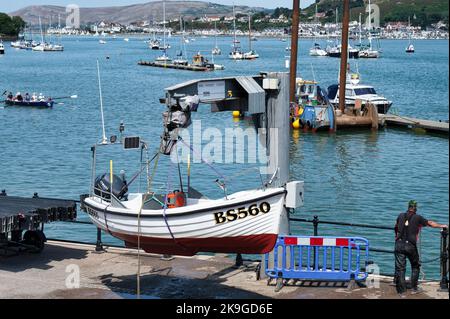 Conwy, UK- July 16, 2022: A small fishing boat getting lifted out of the water at Conwy harbor in the village of Conwy, Northern Wales. Stock Photo