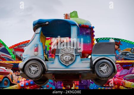 Looking up at the toy police car seat on a children's carousel at the annual Seafront Fun Fair in Bray, Ireland. Cloudy summer day. Stock Photo