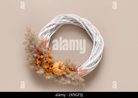 Thanksgiving wreath with pumpkin, orange flowers, dry natural materials on beige background. Top view. Copy space. Stock Photo
