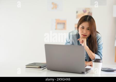 Construction design concept, Female architect use calculator and looks house plan project on laptop. Stock Photo