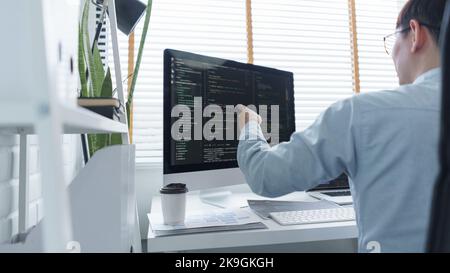 Software development concept, Male programmer checking data codes on document and computer screen. Stock Photo