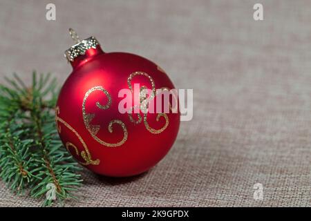 Red Christmas tree ball and spruce branch on jute fabric Stock Photo