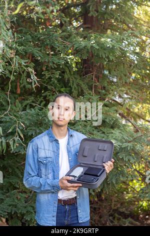 Young man showing a state-of-the-art drone to the camera in his portable briefcase in the middle of nature Stock Photo